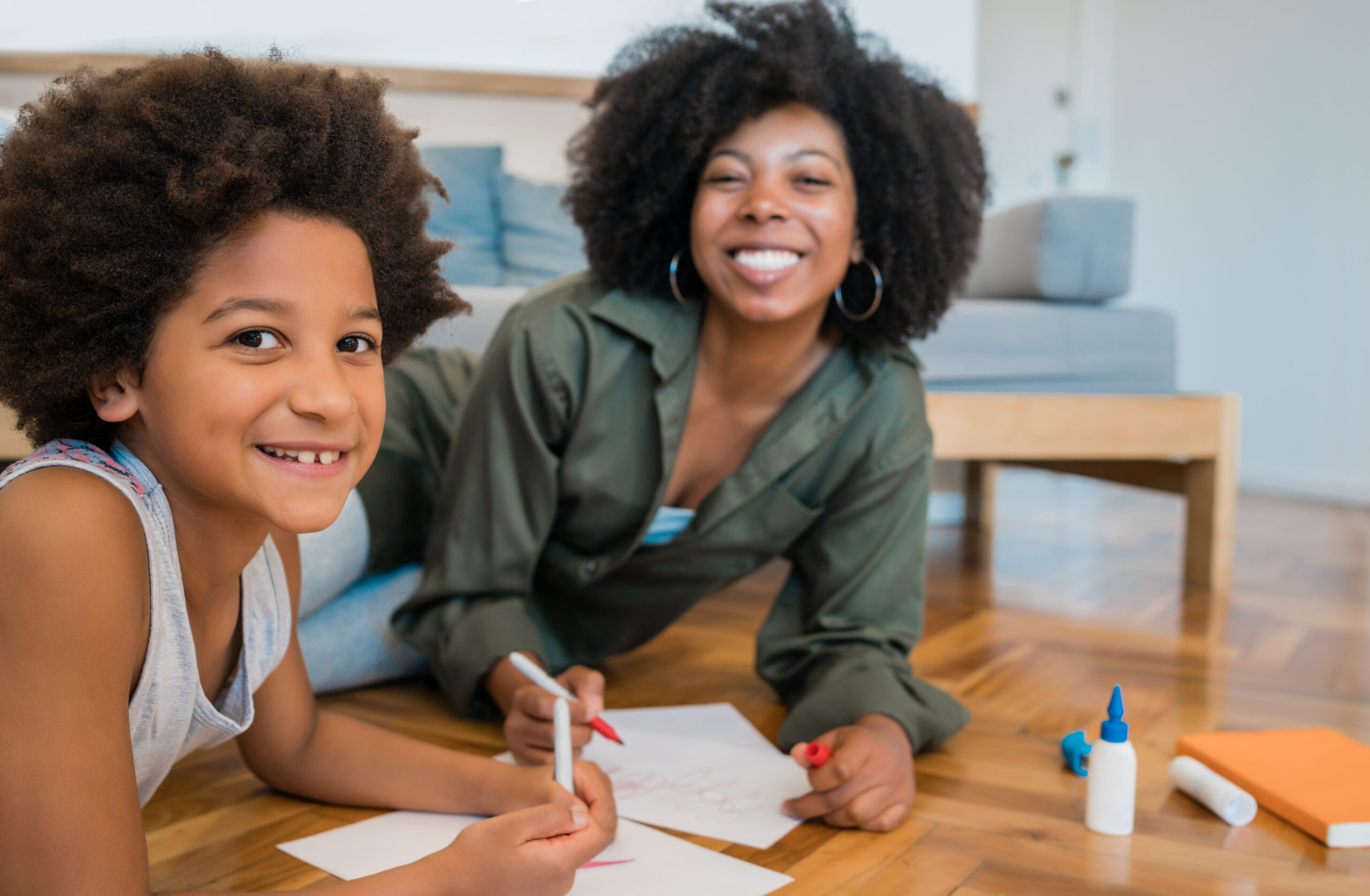 An adult and child drawing on the floor.