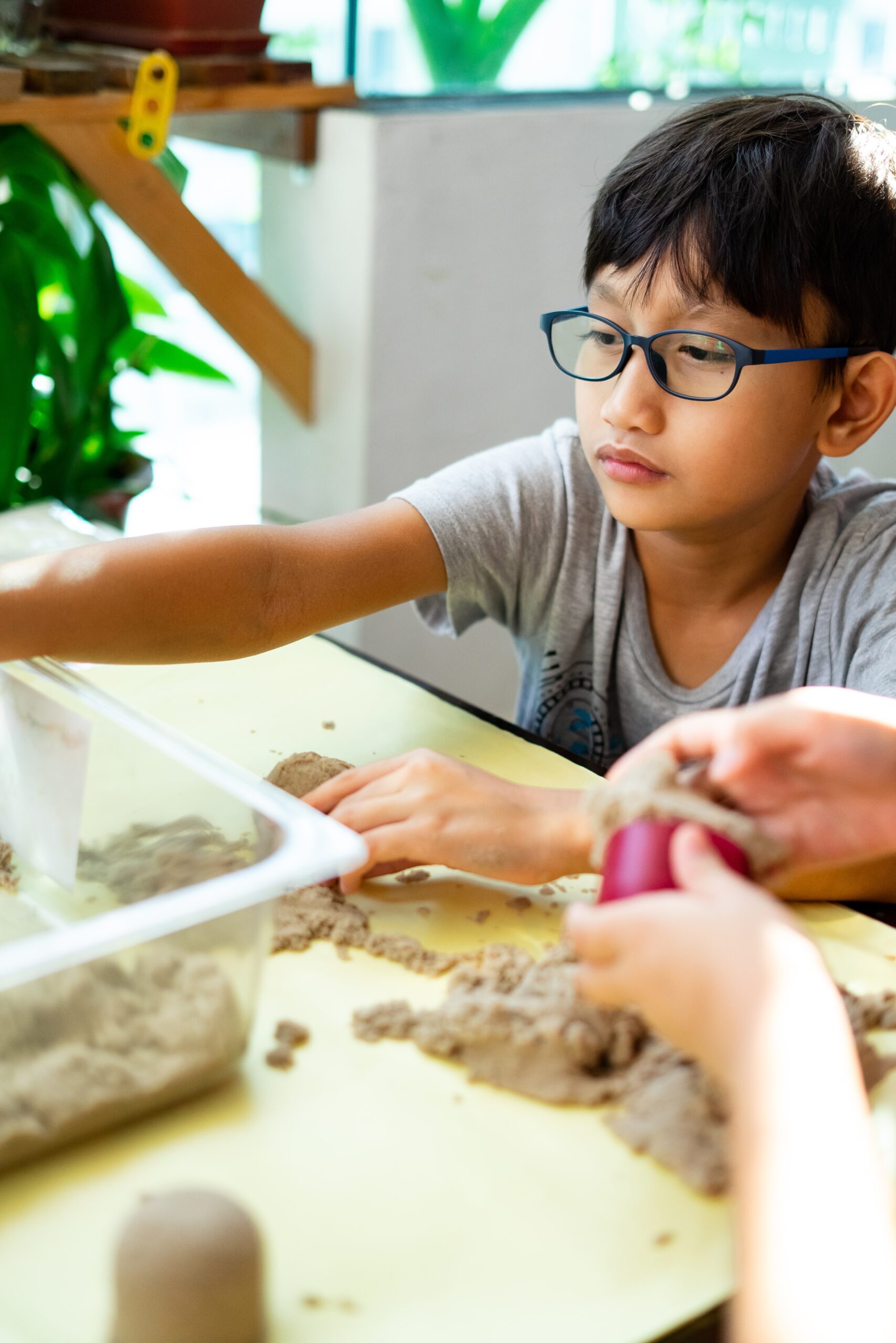 A child exploring kinetic sand at a table.