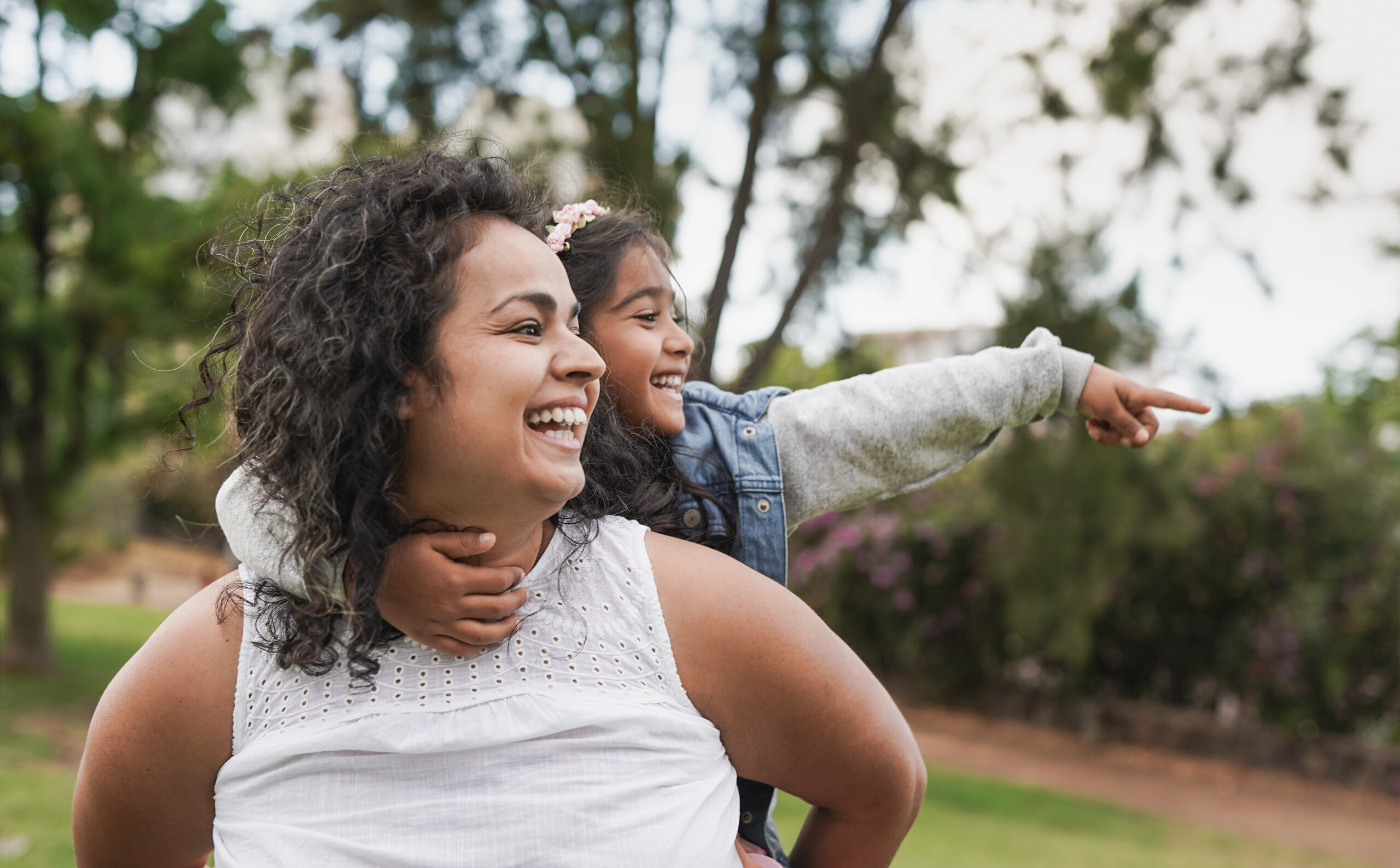 An adult carrying a smiling child outdoors.