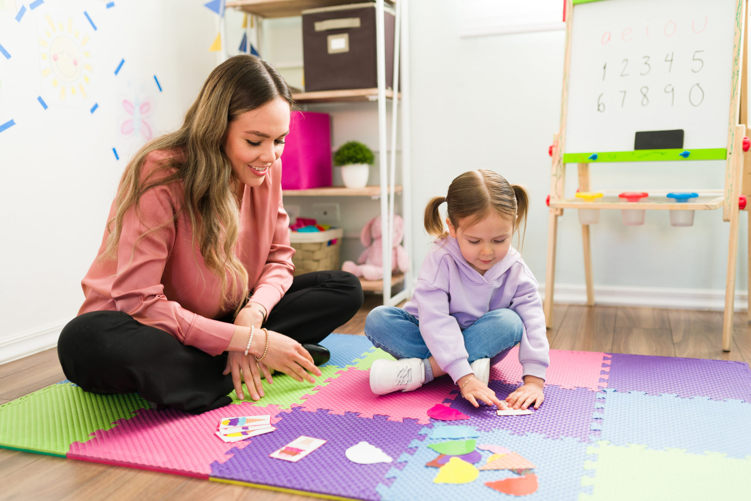 An adult and child working on a floor puzzle.