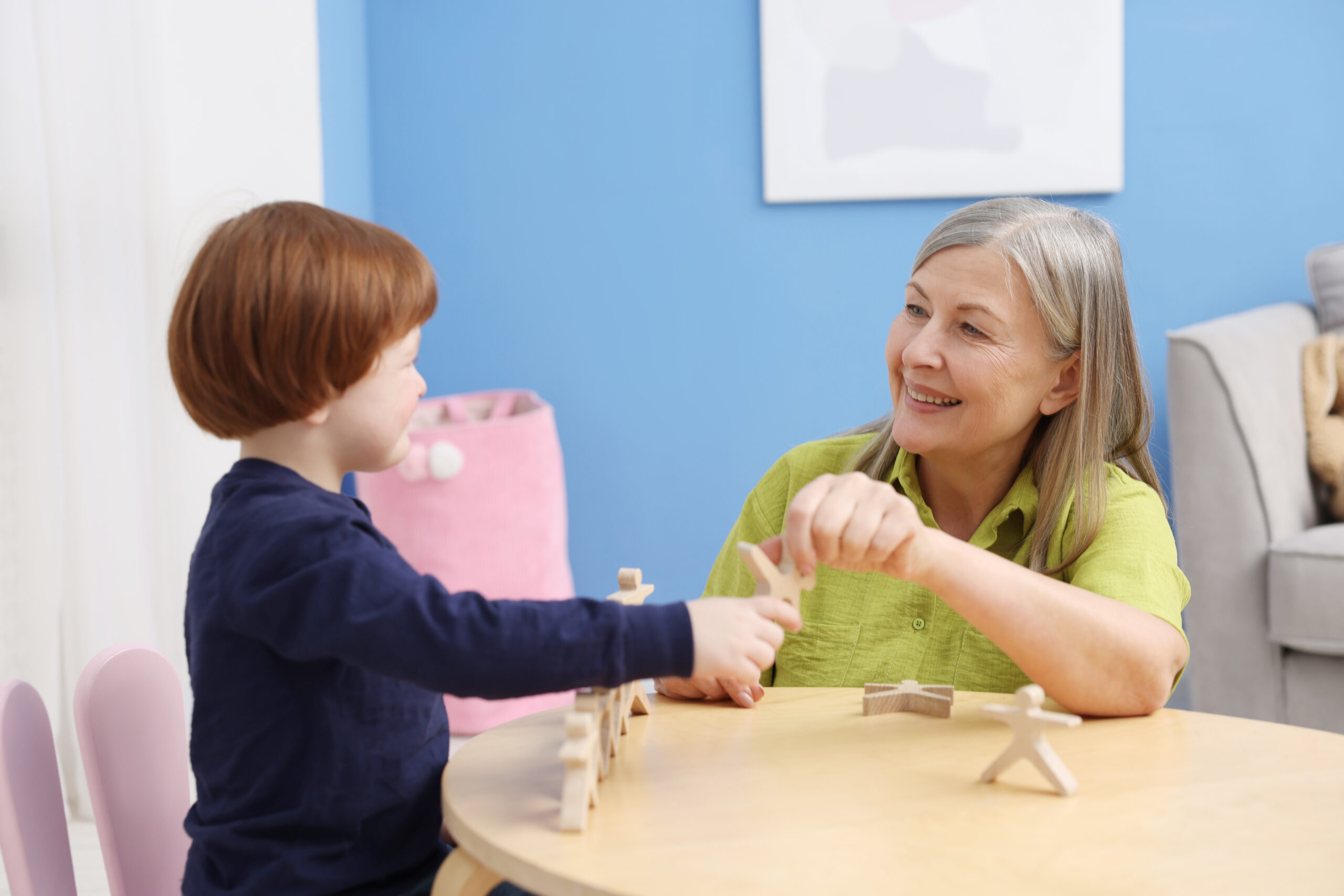 An adult and child playing with wooden figures.