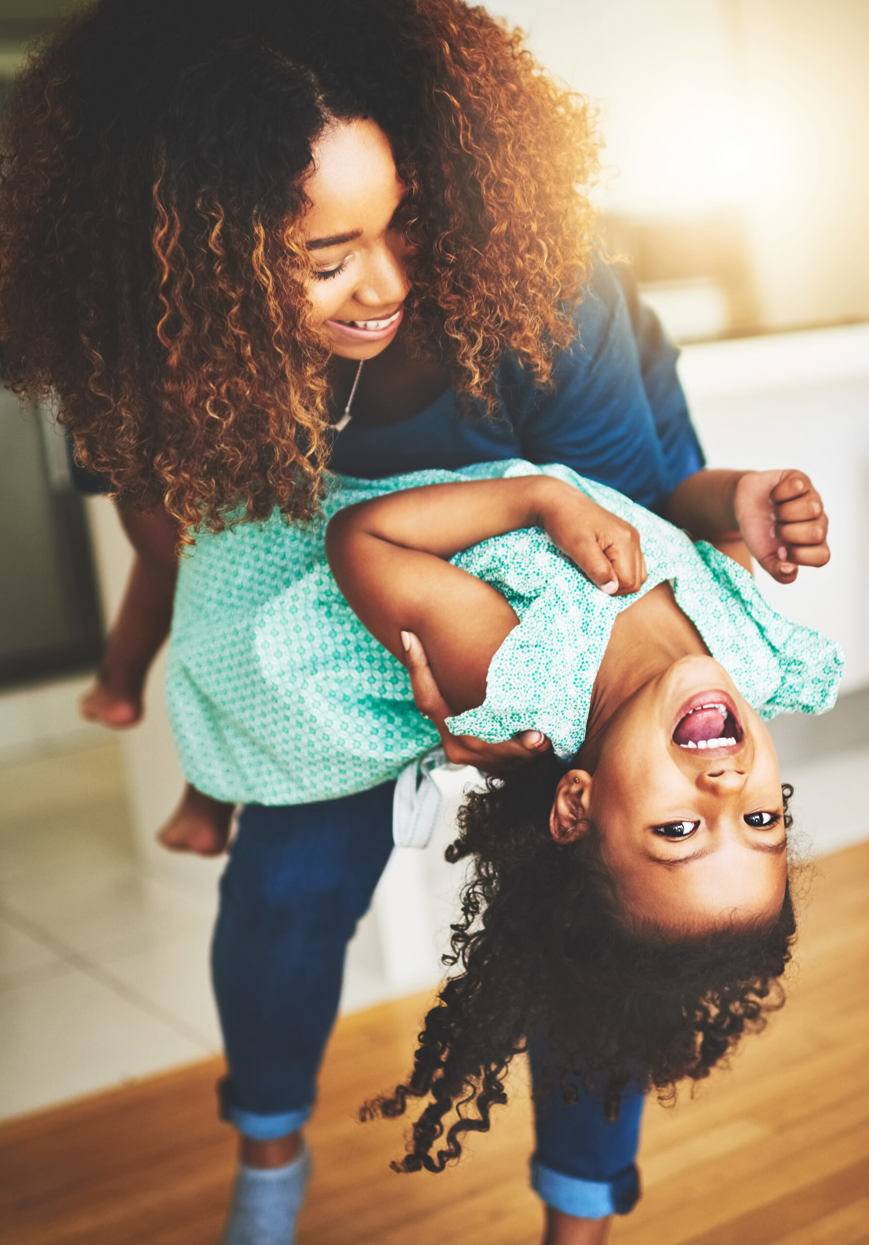 An adult and child enjoying a playful moment at home.