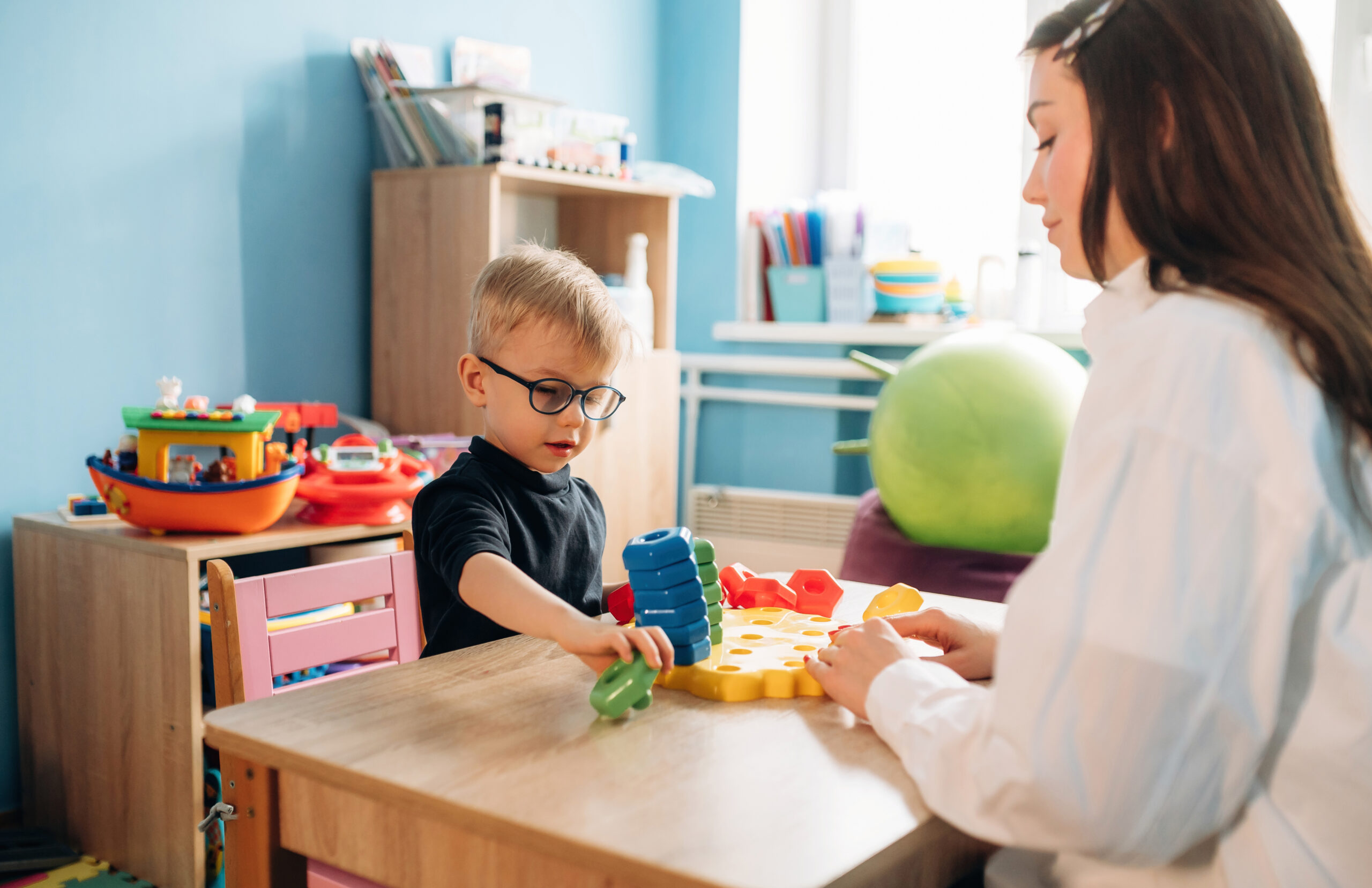 A child and adult using learning materials at a table.